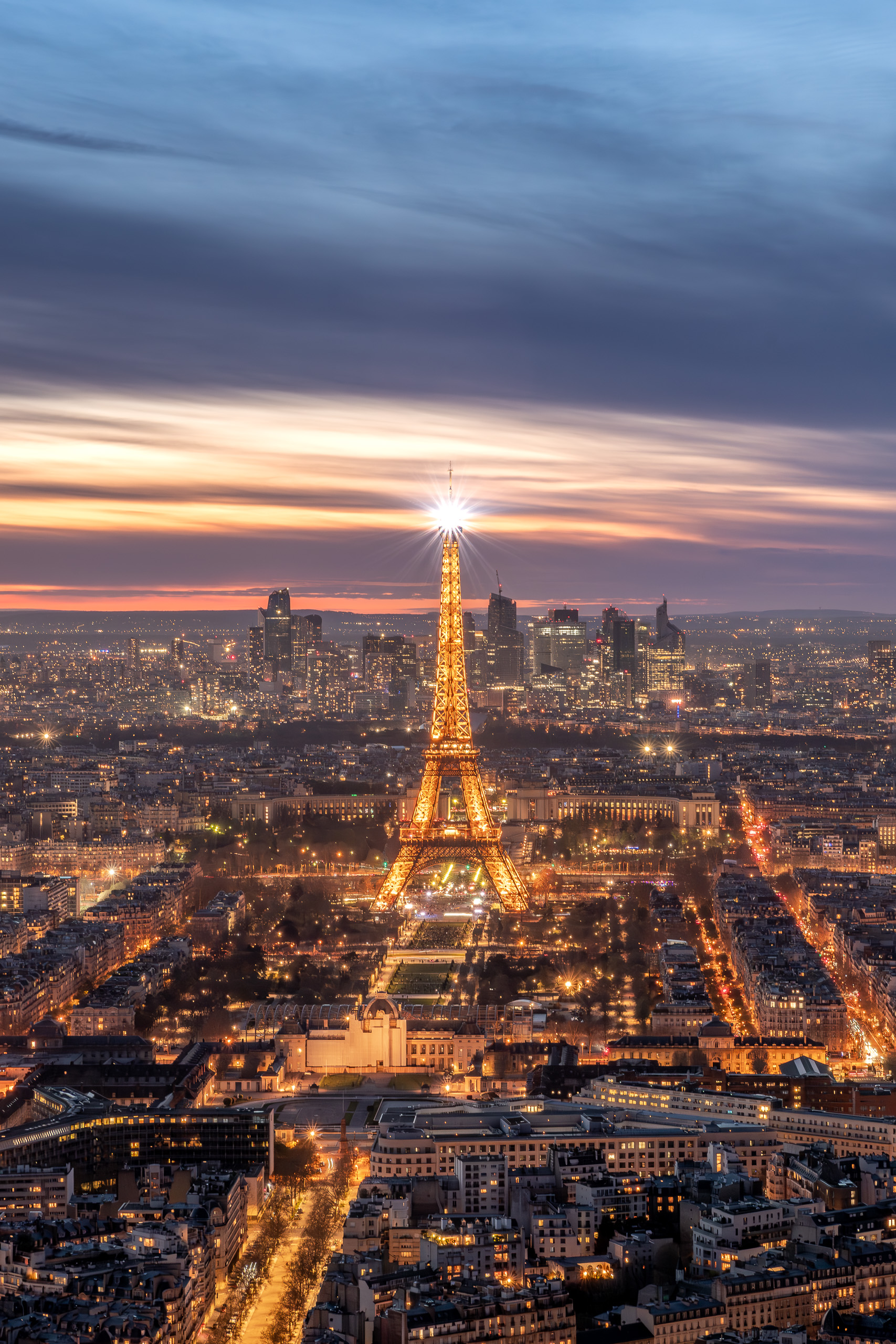 Vertical sunset photograph of Paris with the Eiffel Tower illuminated above the city skyline