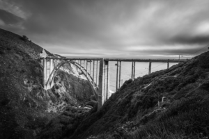 Bixby Creek Bridge in Big Sur California spanning coastal canyon with dramatic clouds in black and white