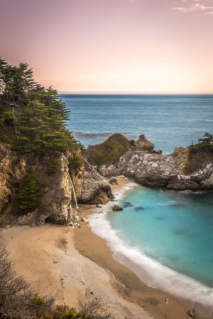 McWay Falls waterfall flowing onto beach in Big Sur California with turquoise water and coastal cliffs