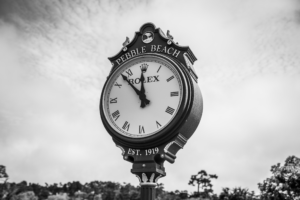 Black and white Pebble Beach Rolex clock sign with cloudy sky in California