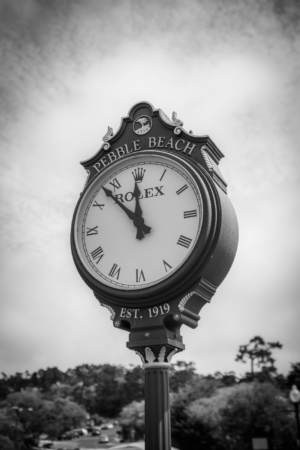 Black and white Pebble Beach Rolex clock sign in California with cloudy sky background