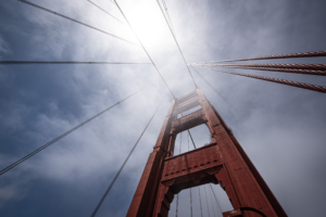 Upward view of Golden Gate Bridge cables and tower disappearing into fog in San Francisco