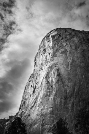 Black and white vertical close-up photograph of El Capitan in Yosemite with dramatic clouds overhead