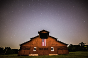 Historic red barn with an American flag beneath a star-filled night sky near Franklin, Tennessee.