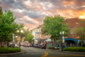 Historic downtown Franklin, Tennessee at sunset with the iconic Gray's on Main neon sign glowing beneath a dramatic sky filled with colorful evening clouds.