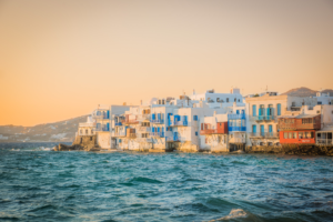 Sunset over Little Venice in Mykonos Greece with whitewashed buildings and blue balconies above the Aegean Sea
