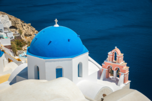 Blue dome church in Santorini Greece overlooking deep blue Aegean Sea