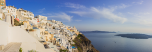 Panoramic view of white cliffside buildings and caldera sea in Santorini Greece