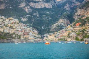 Horizontal photograph of Amalfi Coast Italy harbor village with cliffs boats and blue sea
