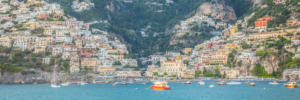 Panoramic photograph of Amalfi Coast Italy hillside village with turquoise sea and boats