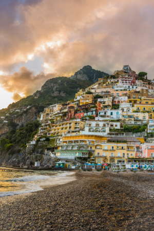 Vertical photograph of Positano beach at sunset on the Amalfi Coast Italy with colorful hillside homes
