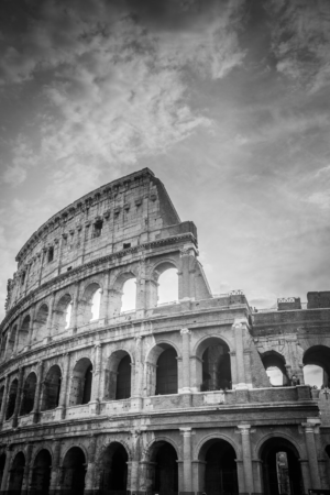 Vertical black and white photograph of the Colosseum in Rome Italy with dramatic sky above