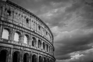 Black and white close view of the Colosseum in Rome Italy with dramatic storm clouds overhead