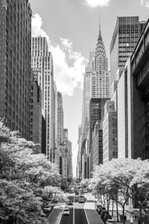 Black and white vertical view down 42nd Street in New York City with the Chrysler Building above Manhattan streets