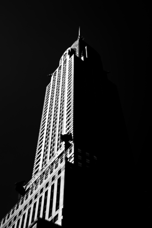 Black and white vertical view of the Chrysler Building rising dramatically against a dark New York sky