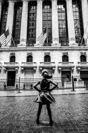 Fearless Girl statue facing Wall Street in black and white in New York City