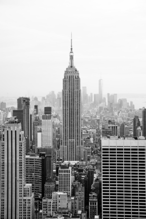 Black and white vertical photo of Empire State Building above the New York City skyline