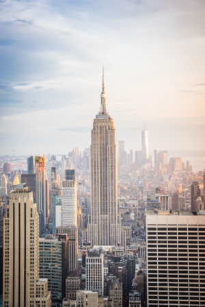 Vertical view of Empire State Building rising above the New York City skyline at sunset
