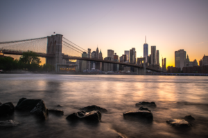 New York City skyline and Brooklyn Bridge at sunset from the East River shoreline
