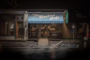 The Bluebird Cafe in Nashville Tennessee at night with glowing sign and wet street reflections