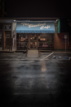 The Bluebird Cafe in Nashville Tennessee at night with illuminated sign and reflections on wet pavement