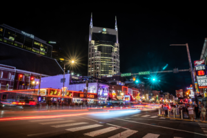 Downtown Nashville Broadway at night with neon lights traffic trails and Batman Building skyline
