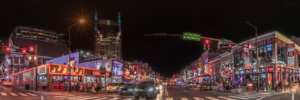 Panoramic night view of Broadway in downtown Nashville Tennessee with neon honky tonks and Batman Building skyline