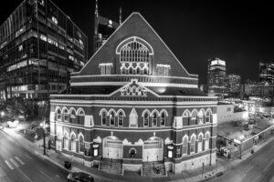 Black and white night photo of Ryman Auditorium in Nashville Tennessee with downtown skyline