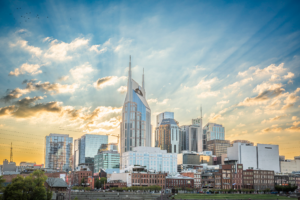 Nashville Tennessee skyline at sunset with sun rays through clouds over downtown buildings