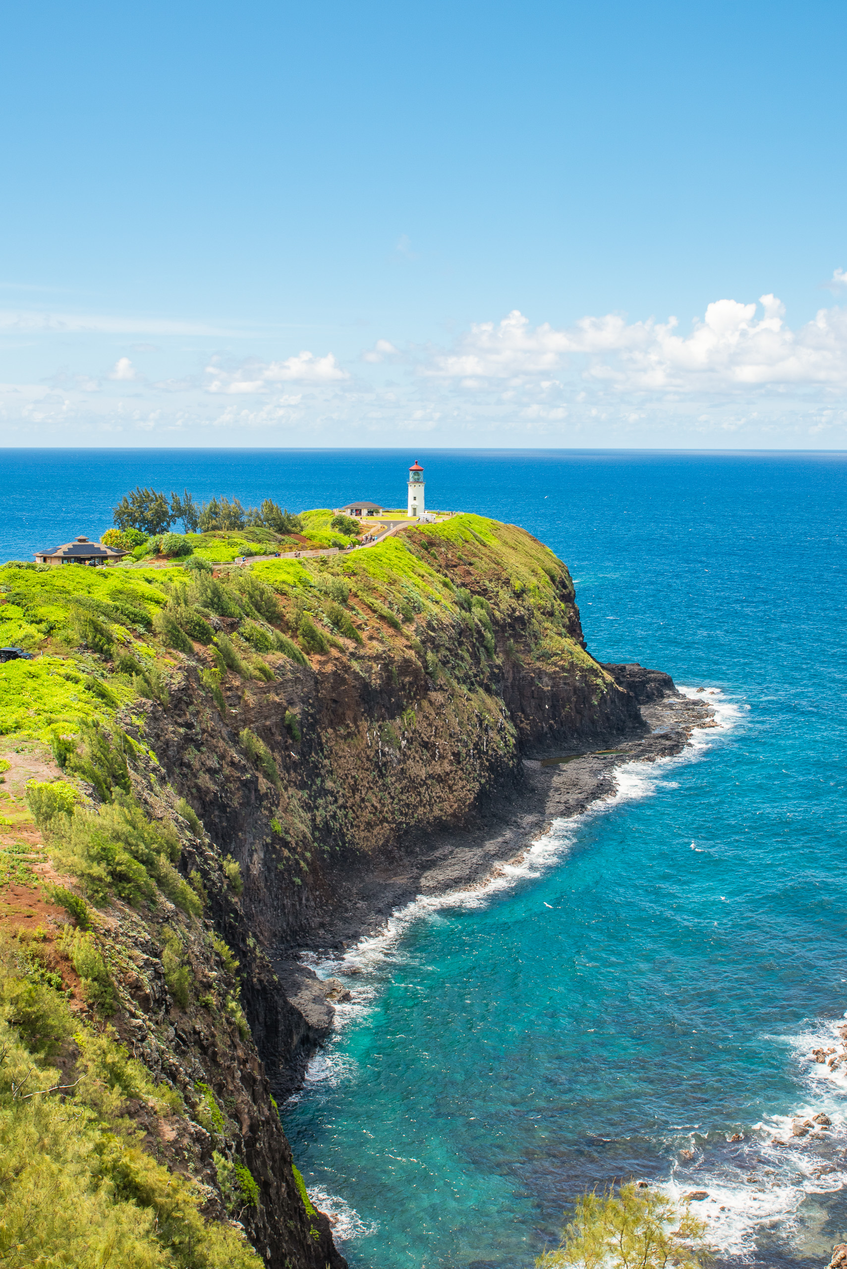 Kilauea Lighthouse on cliffs in Kauai Hawaii overlooking turquoise ocean and rugged coastline