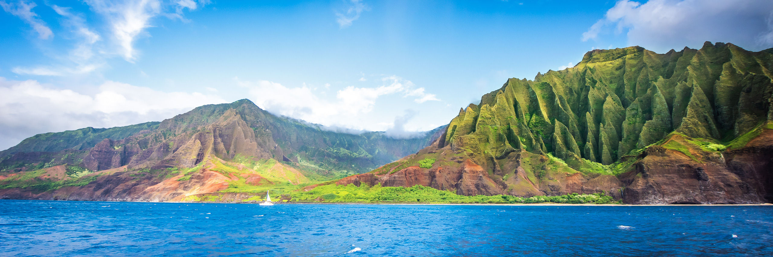 Na Pali Coast on Kauai Hawaii with emerald cliffs rising above deep blue Pacific Ocean panorama
