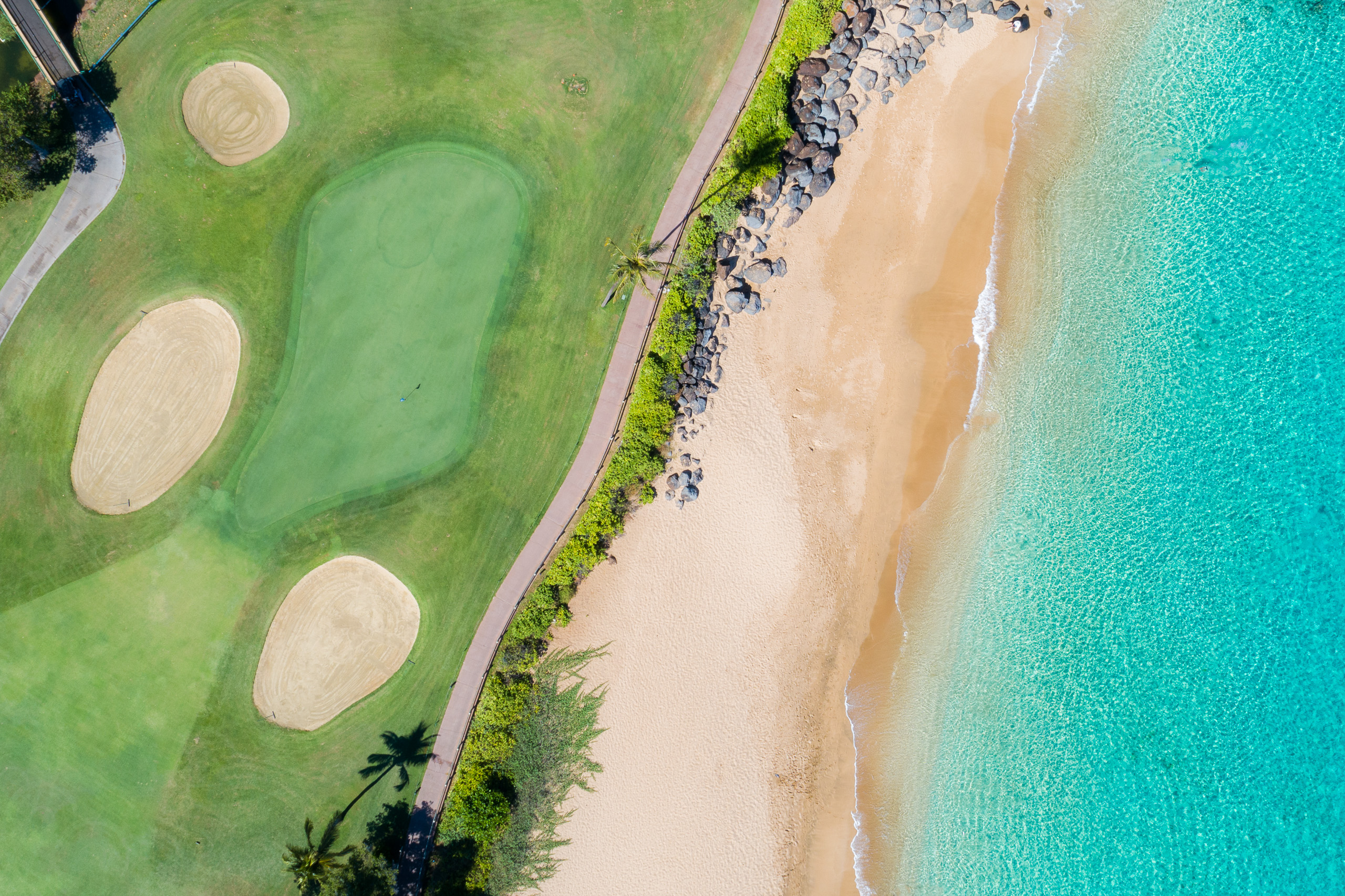 Aerial view of Maui Hawaii golf course beside tropical beach with turquoise ocean, white sand and green fairway