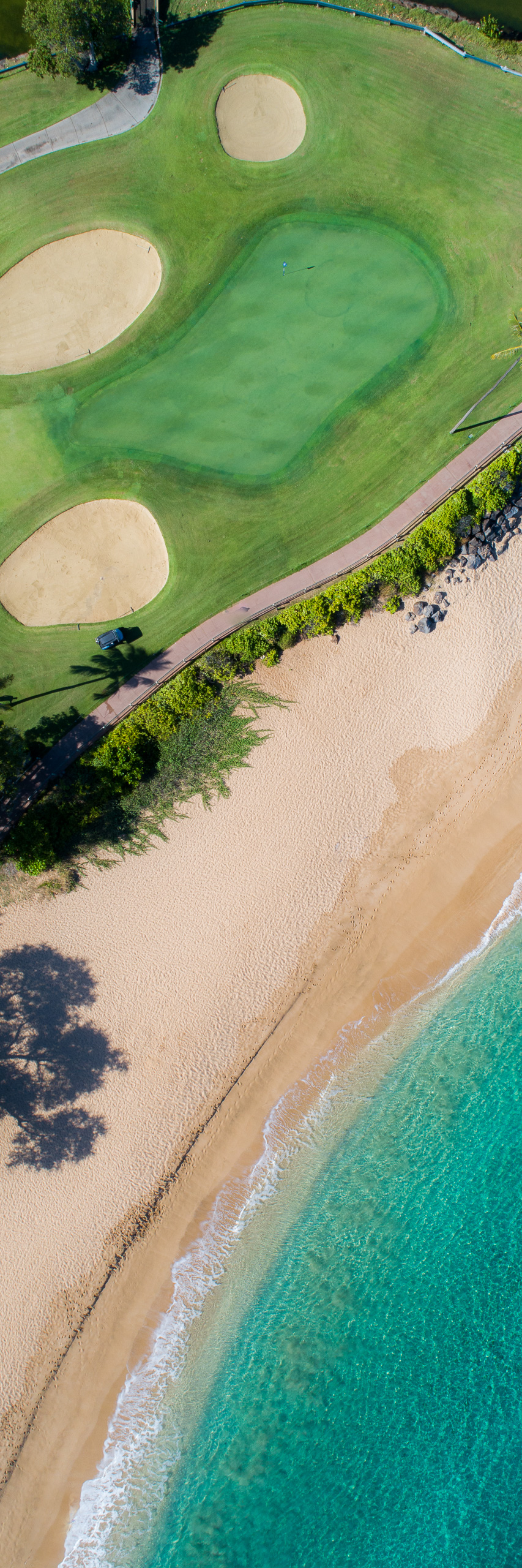 Aerial panorama of Maui Hawaii golf course next to sandy beach and turquoise ocean shoreline