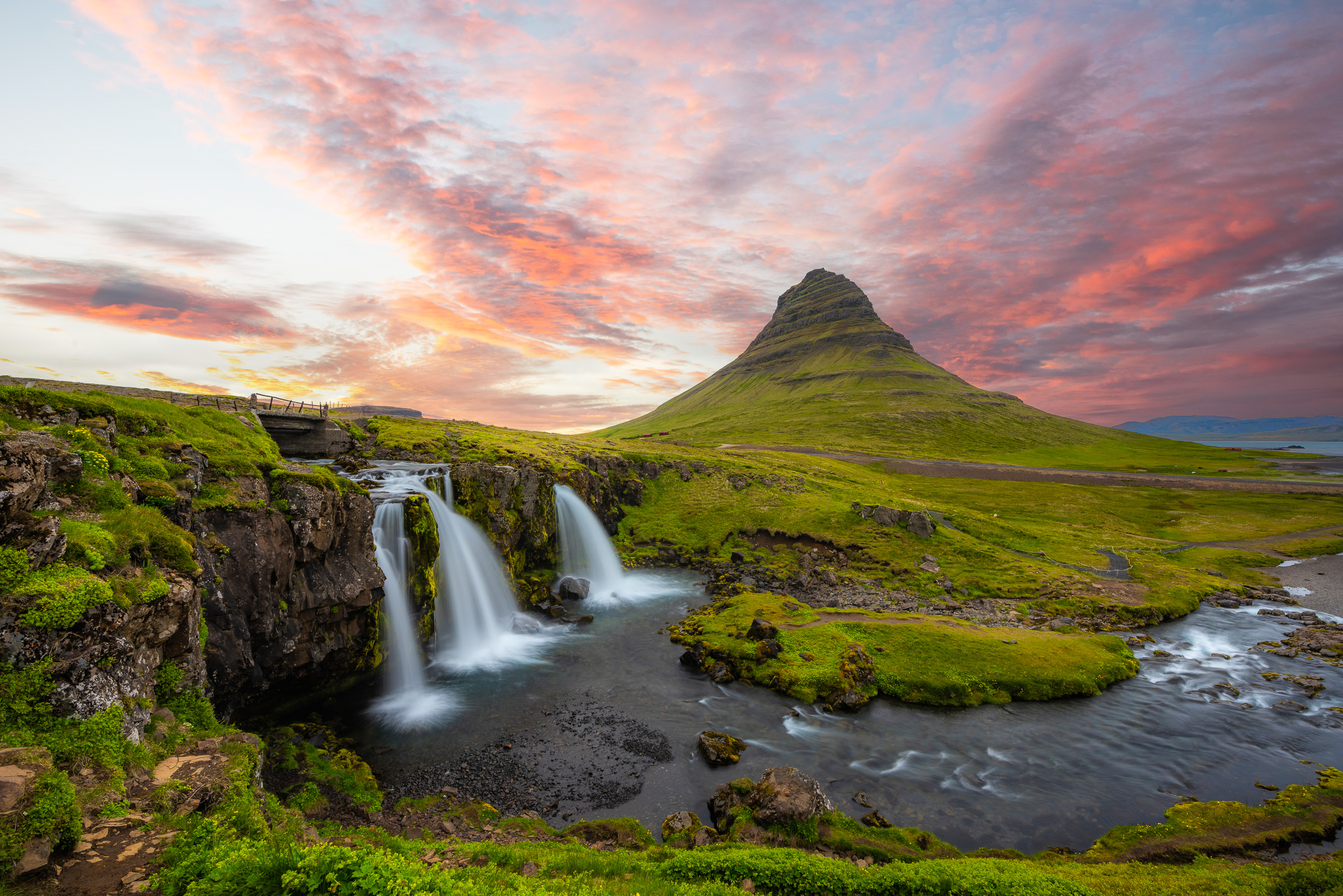 Kirkjufell mountain and waterfall in Iceland at sunset with colorful pink clouds