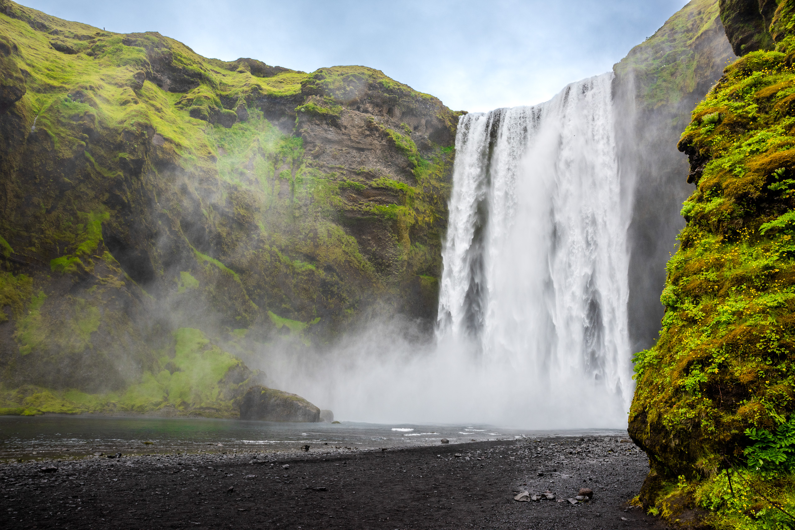Skogafoss waterfall with mist and moss covered cliffs in Iceland landscape