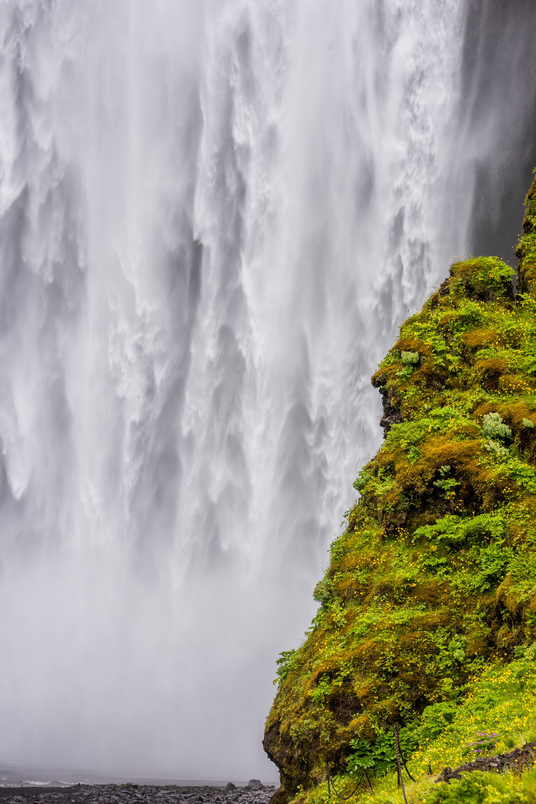 Vertical close view of Skogafoss waterfall with moss covered cliff in Iceland