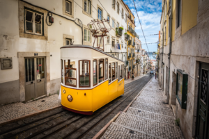 Yellow Lisbon funicular tram on steep cobblestone street in Portugal