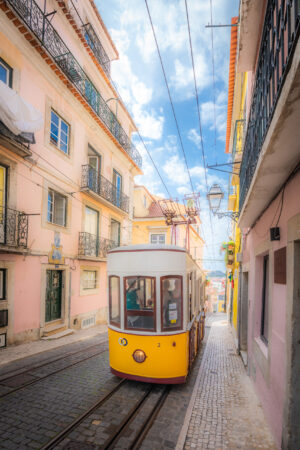 Yellow Lisbon funicular tram on narrow cobblestone street in Portugal