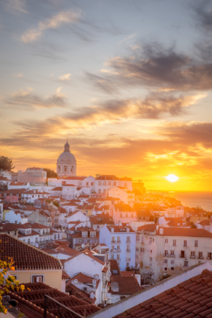 Sunrise over historic rooftops and church dome in Lisbon Portugal