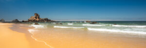 Panoramic beach view with golden sand, waves, and rock formations on the west coast of Portugal