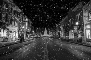 Black and white snowy Main Street in downtown Franklin Tennessee with Christmas tree and holiday lights at night