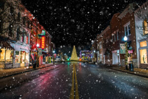 Snowfall on downtown Franklin Tennessee Main Street with Christmas tree and holiday lights at night
