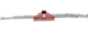 Red barn in snowy field near Franklin Tennessee with American flag and winter trees panorama