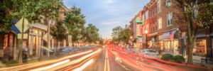 Panoramic long exposure of historic downtown Franklin, Tennessee, featuring the iconic Gray's on Main neon sign and colorful light trails along Main Street at dusk.