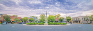 Panoramic view of the historic downtown square in Franklin, Tennessee, featuring the Confederate Memorial monument, colorful storefronts, and dramatic clouds overhead.