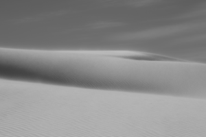 White gypsum sand dunes at White Sands National Park rendered in black and white, showcasing delicate textures, sweeping curves, and a minimalist desert landscape.
