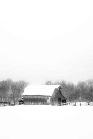 Black and white photograph of a rustic barn surrounded by snow in Franklin, Tennessee
