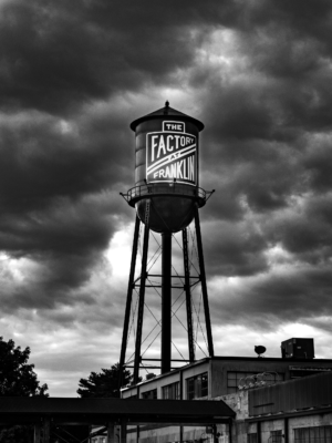 Black and white photograph of The Factory at Franklin water tower beneath dramatic storm clouds in Franklin, Tennessee
