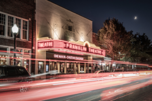 Long exposure photograph of the historic Franklin Theatre at night in downtown Franklin, Tennessee, with passing car light trails