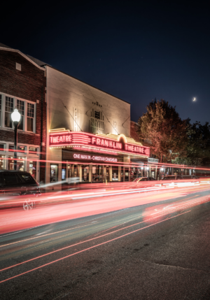 Vertical long exposure photograph of the historic Franklin Theatre at night in downtown Franklin, Tennessee, with red car light trails